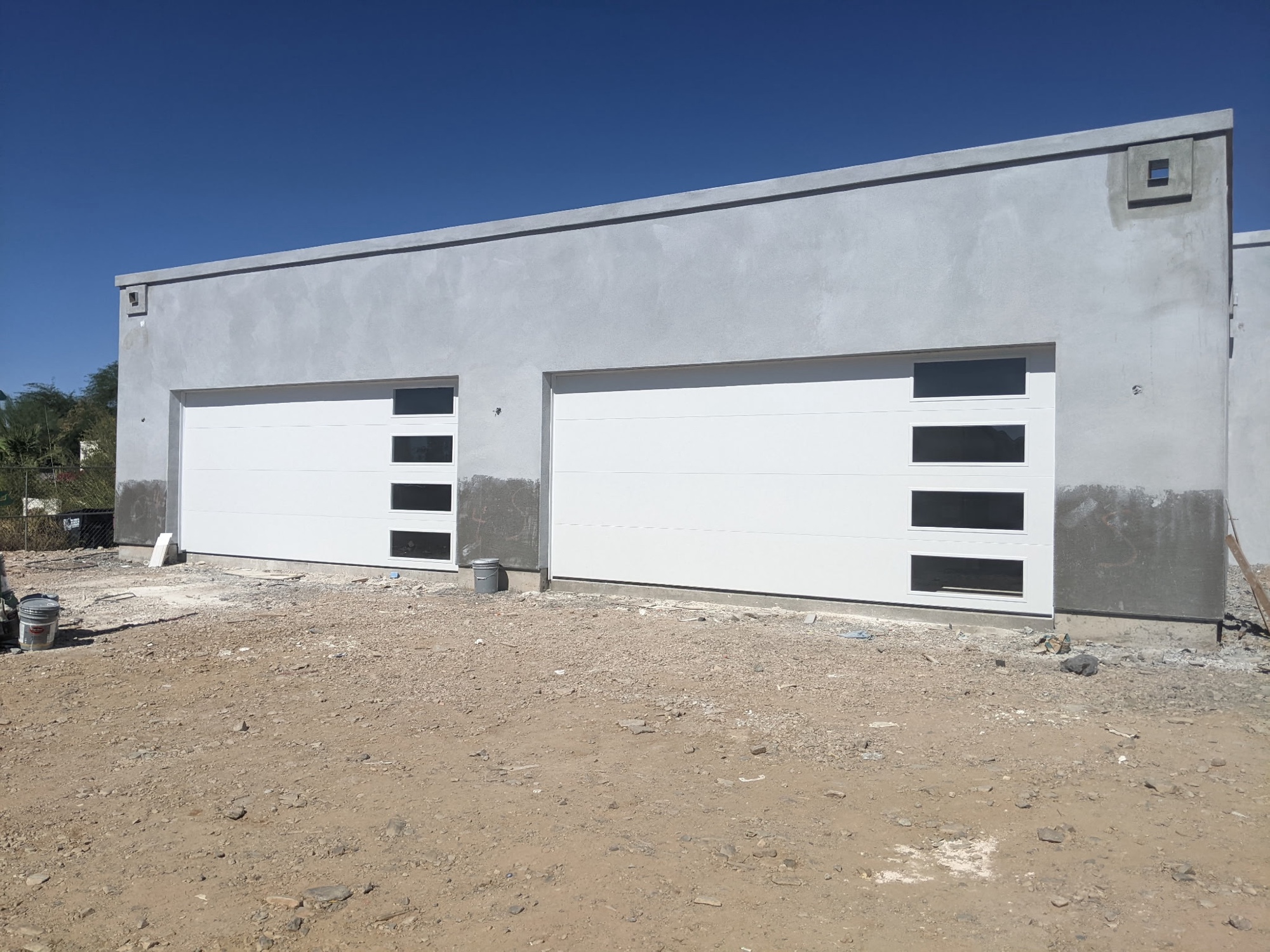 White contemporary garage doors with side-lite windows on new construction
